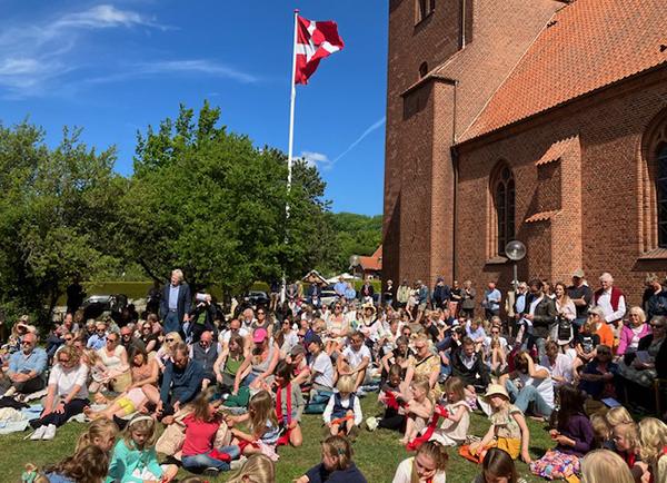 En festlig udendørs gudstjeneste fejres med glade mennesker og forskellige aktiviteter